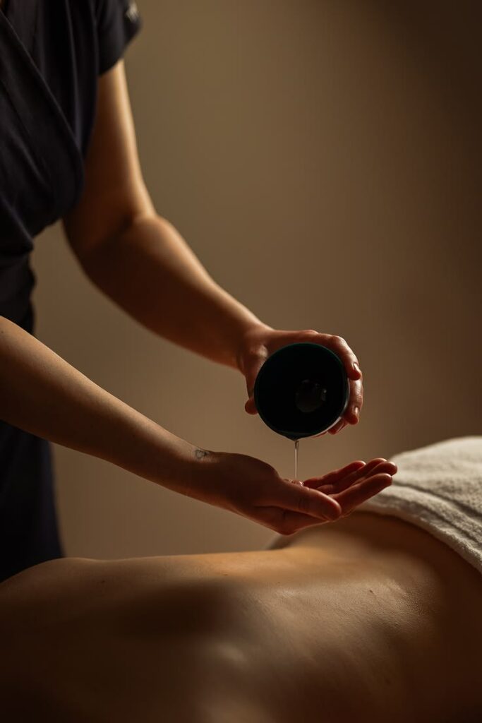 Therapist pouring warm massage oil for body therapy session at Holistic Luxury Spa & Salon, Bhopal